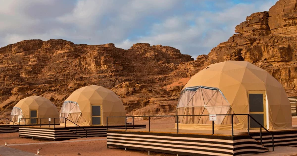 Glamping domes at Jamal Rum Camp with sandstone cliffs behind them.